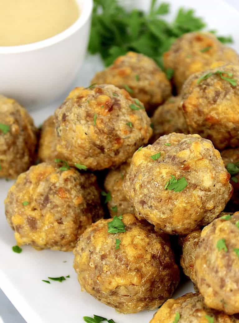 sausage balls on white plate with honey mustard on side