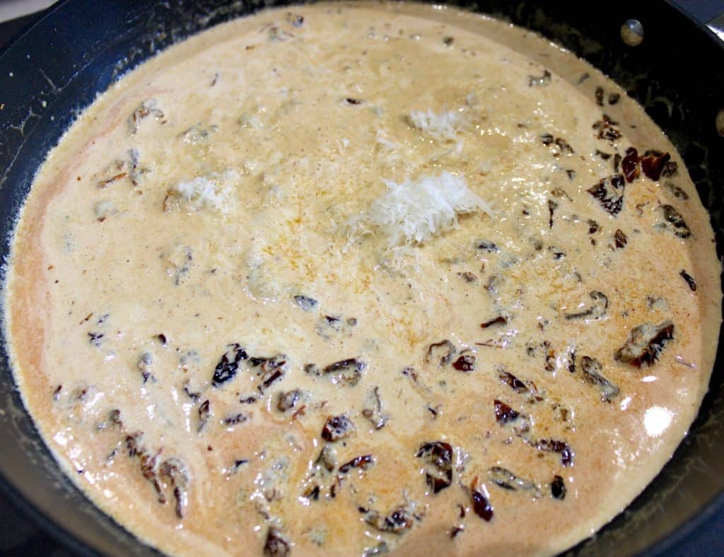 tuscan cream sauce in skillet with parmesan cheese on top
