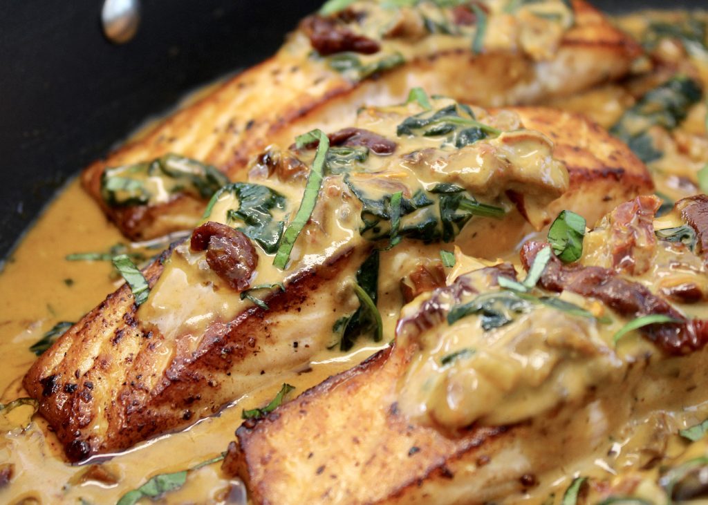 closeup of tuscan salmon in skillet with sauce on top