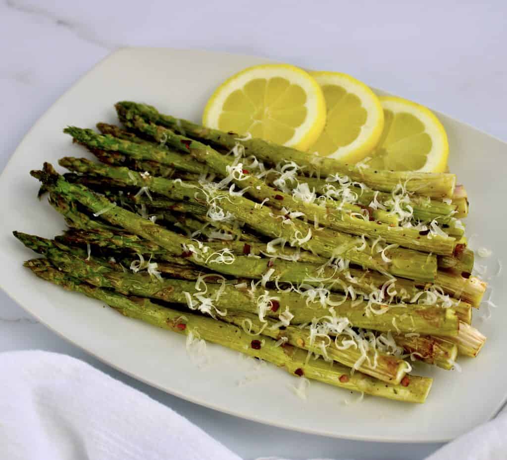 closeup of roasted asparagus with grated cheese and lemon slices