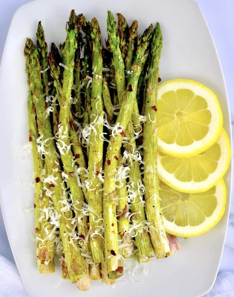 roasted asparagus on white plate with grated parmesan 3 lemon slices