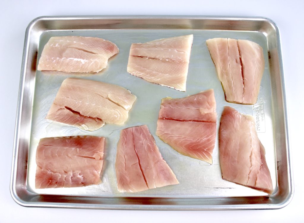 8 pieces of raw red snapper on baking sheet