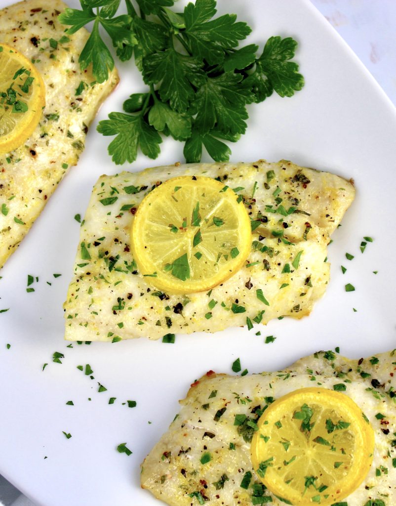 piece of baked snapper with herbs and slice of lemon on top