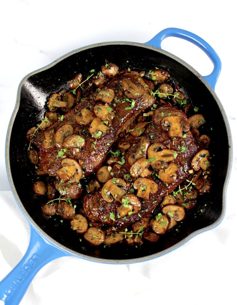 2 sautéed steaks with mushrooms in skillet