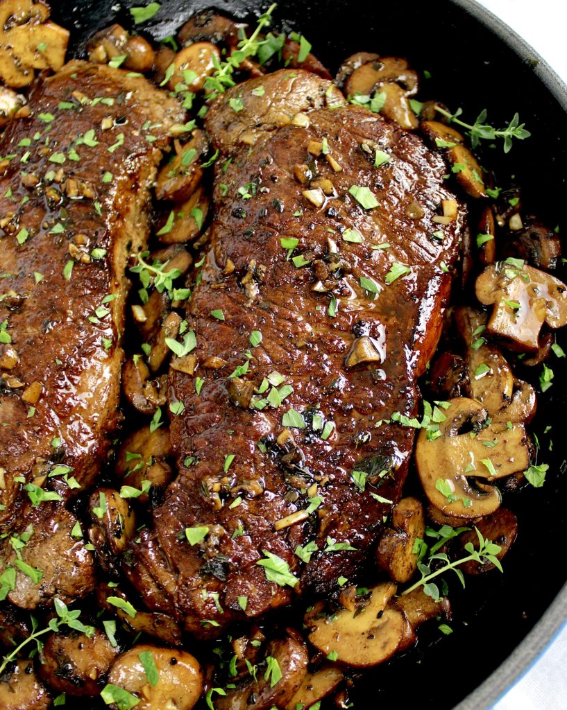 overhead view of steak in skillet with sautéed mushrooms