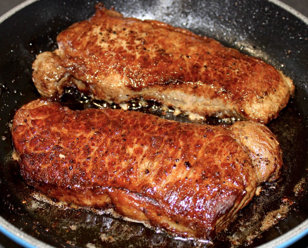 2 seared steaks in skillet