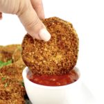 piece of fried eggplant being dipped in marinara sauce
