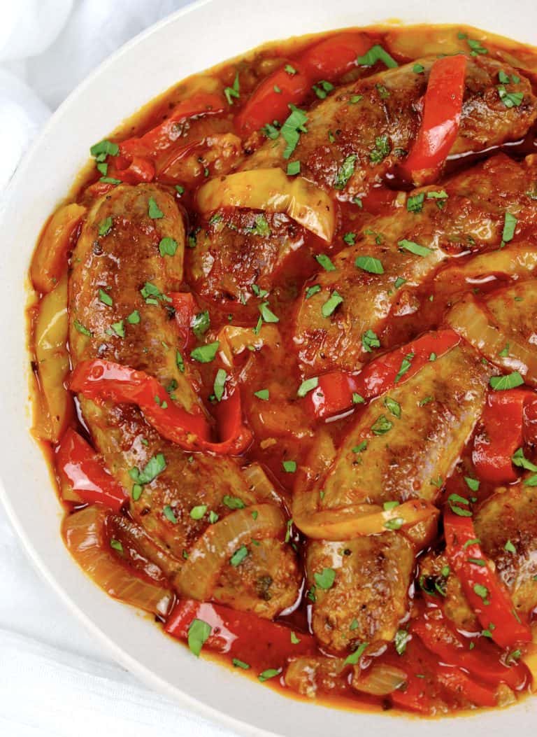 sausage with red and yellow peppers in marinara sauce in white bowl