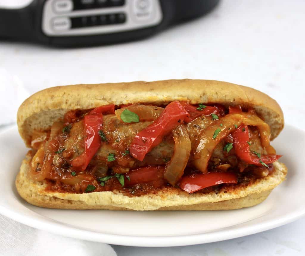 sausage and peppers in bun with crockpot in background
