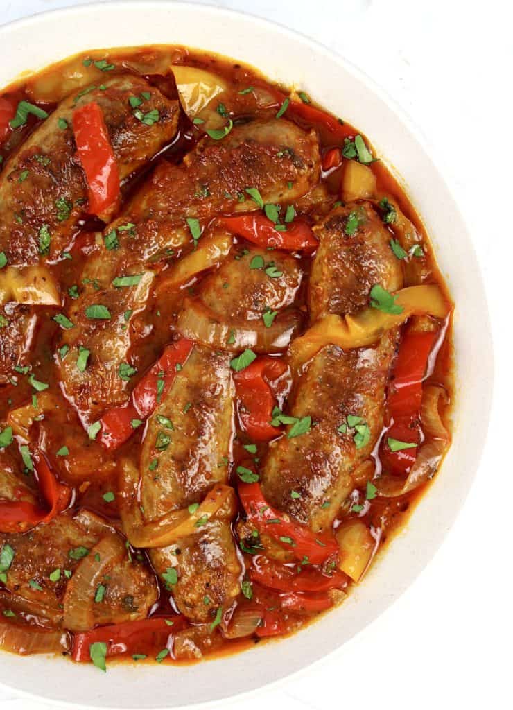 sausage with red and yellow peppers in marinara sauce in white bowl