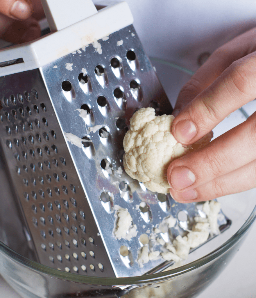 cauliflower being grated on box grater