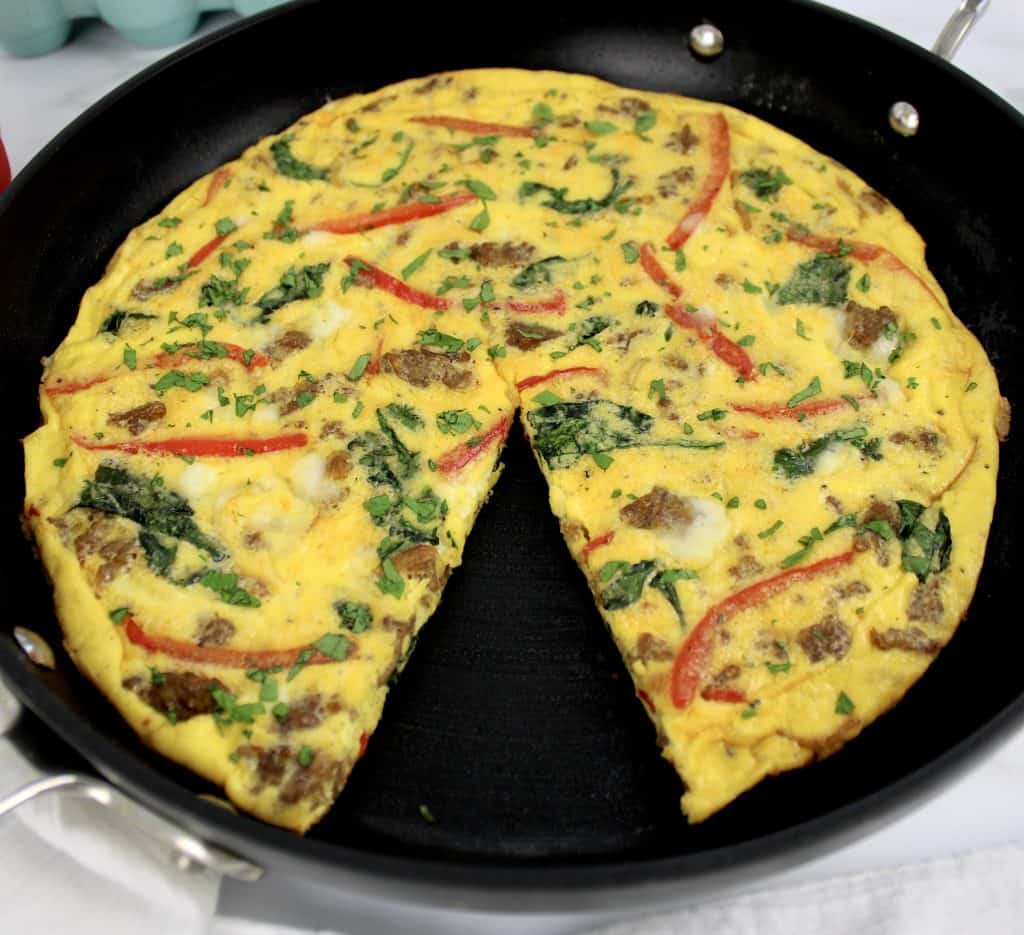 sausage and pepper frittata in skillet with slice missing