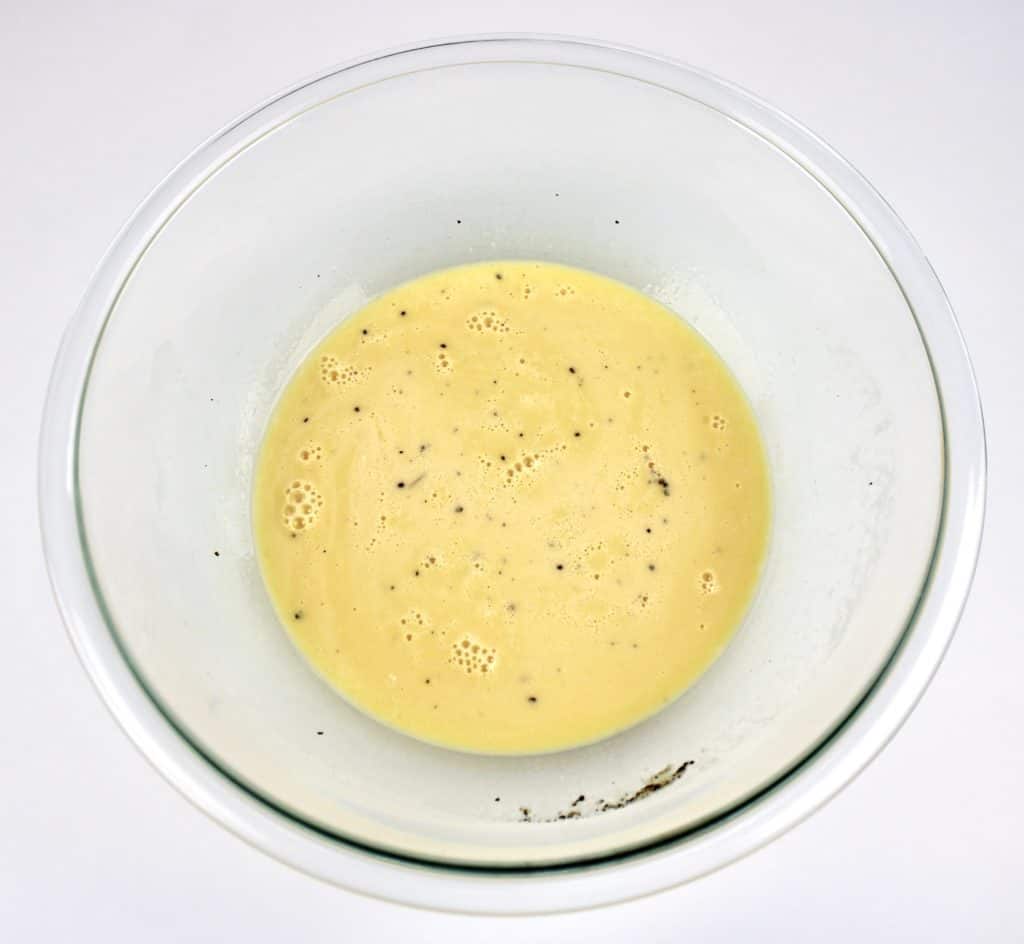 beaten eggs with pepper and cream in glass bowl