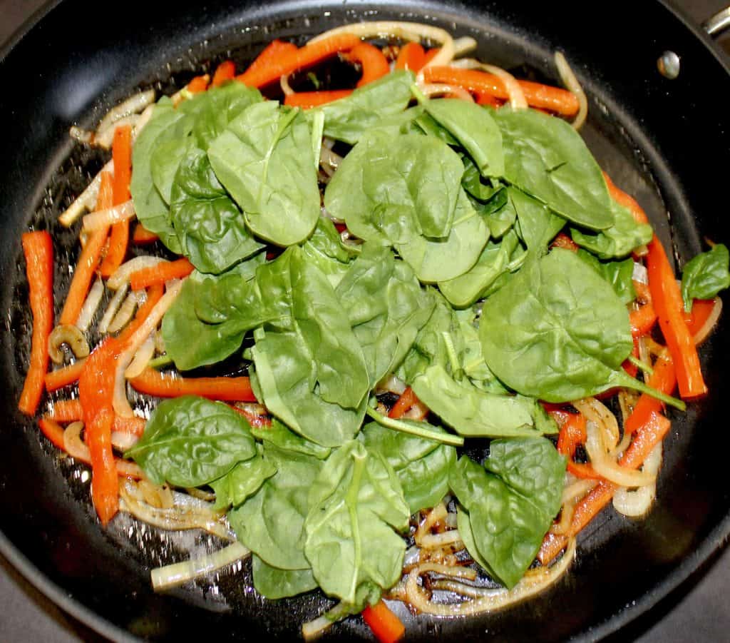 red pepper onions and raw spinach in skillet