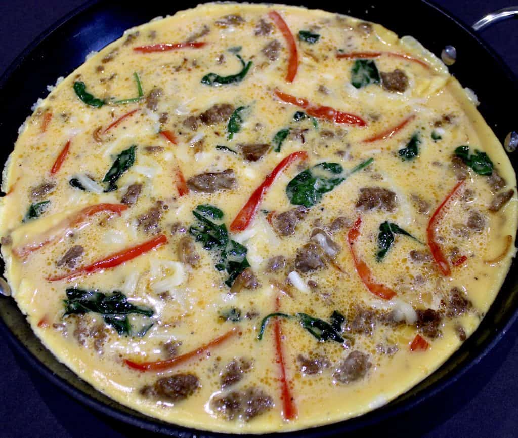 uncooked sausage and peppers frittata in skillet