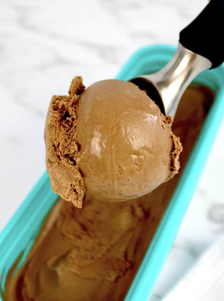 scoop of chocolate ice cream held up over container