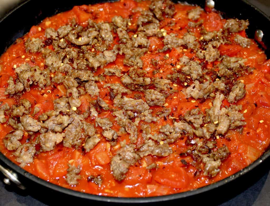 cooked ground sausage over chunky tomato sauce in skillet