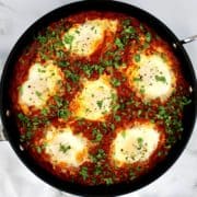 Shakshuka with Italian Sausage and 6 cooked eggs with parsley garnish
