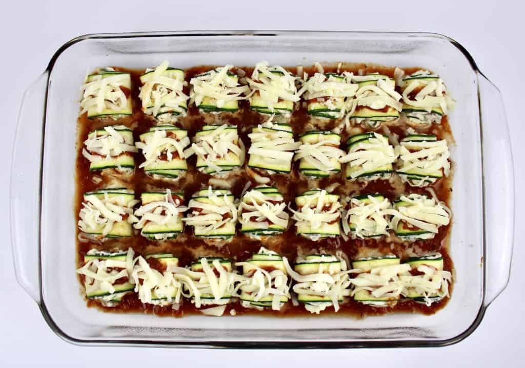 28 Zucchini Rollatini in casserole dish unbaked with shredded mozzarella on top