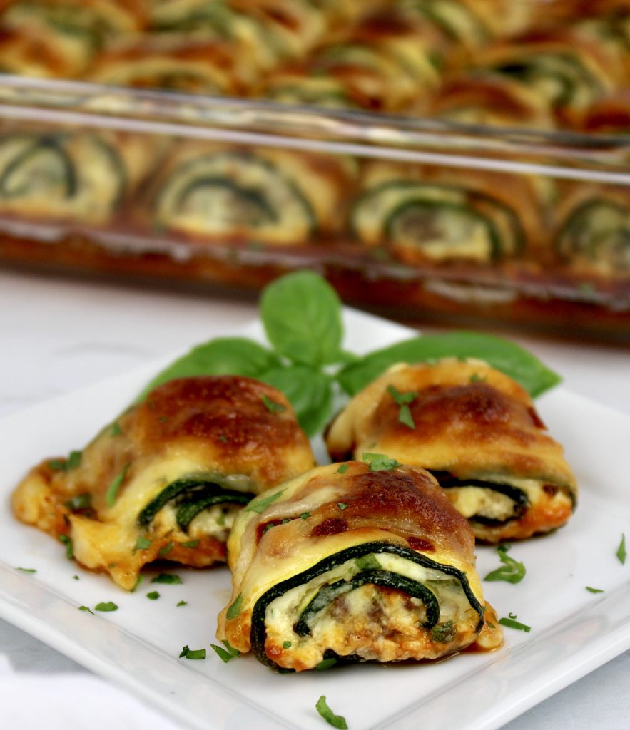 3 Zucchini Rollatini on white plate with casserole in background