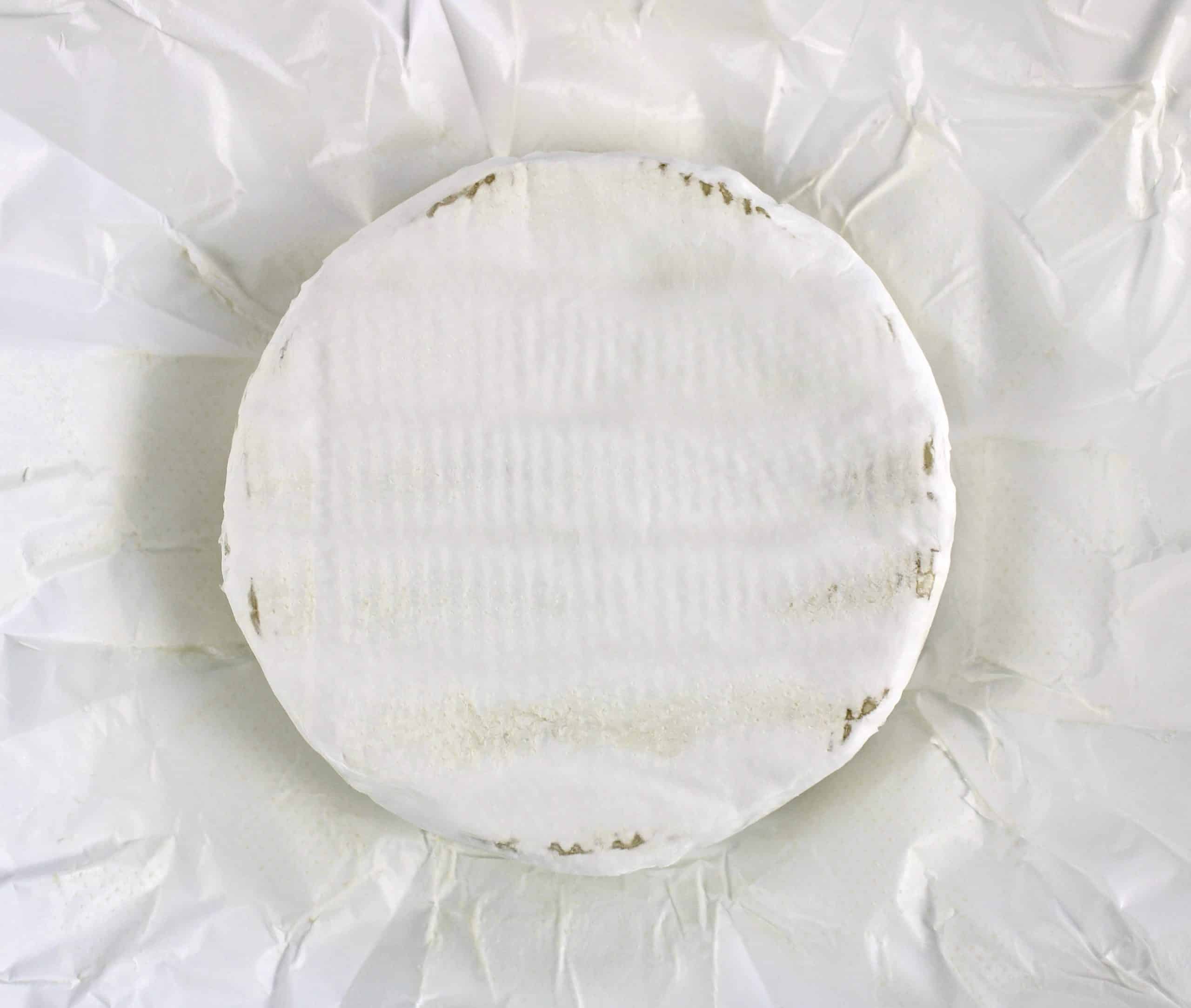 wheel of brie sitting on white wrapper