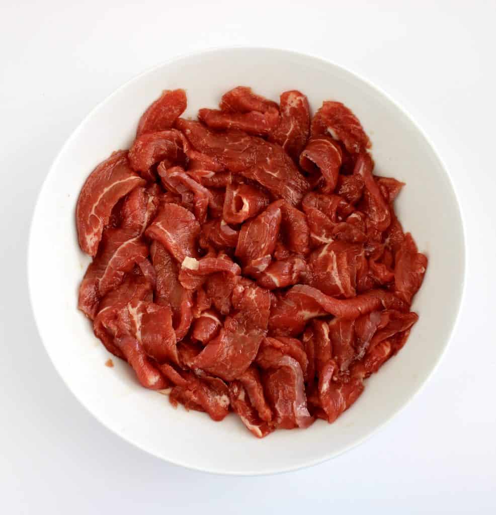 thinly sliced beef in white bowl with light marinade