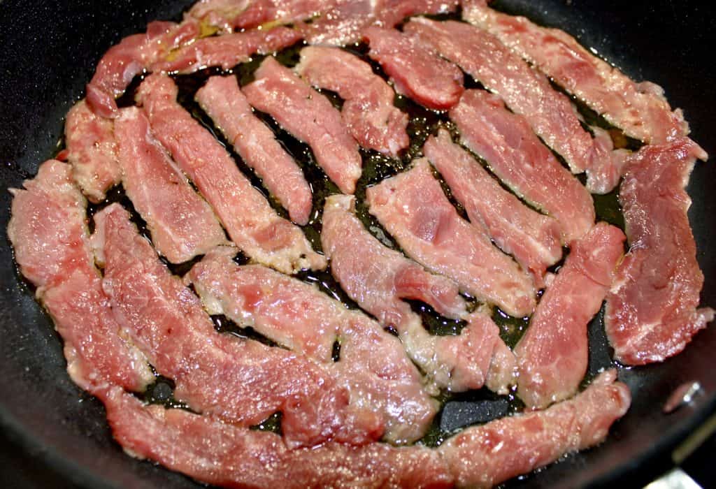 thin slices of steak cooking in skillet