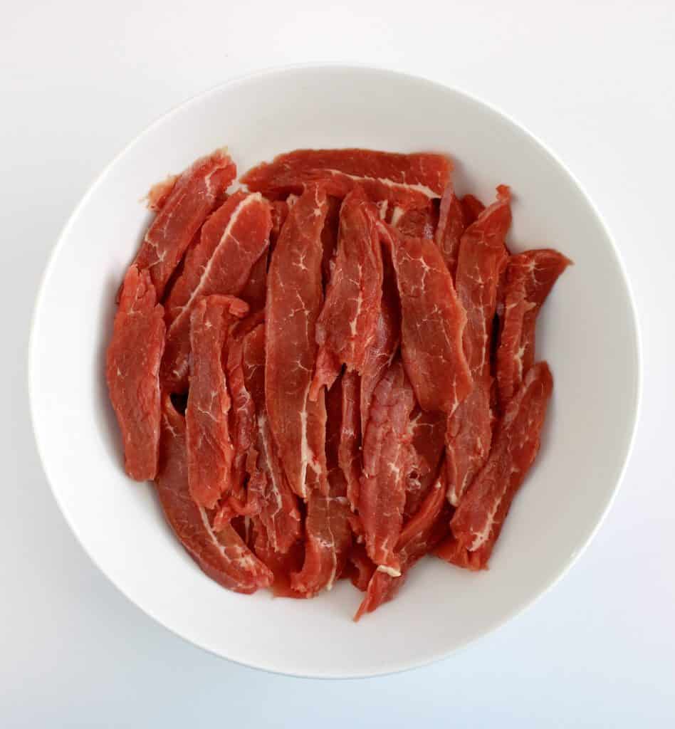 thinly sliced steak in white bowl