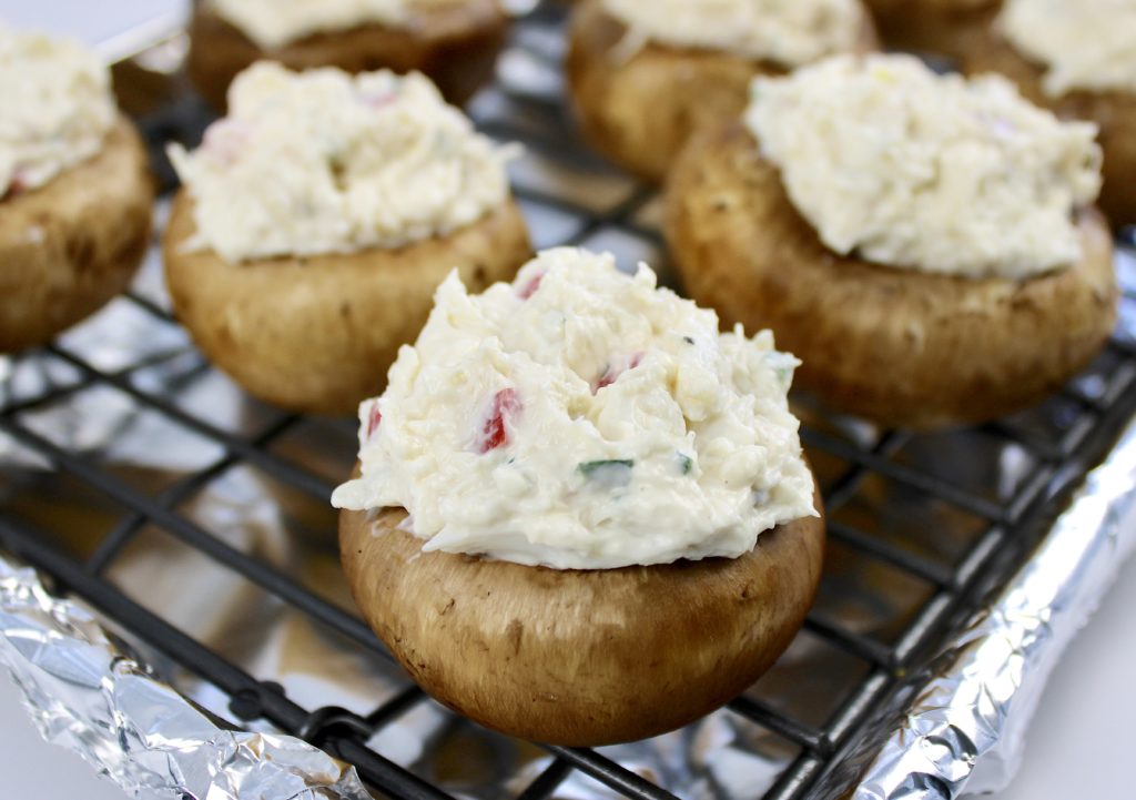 Crab Stuffed Mushrooms unbaked on baking rack lined with aluminum foil