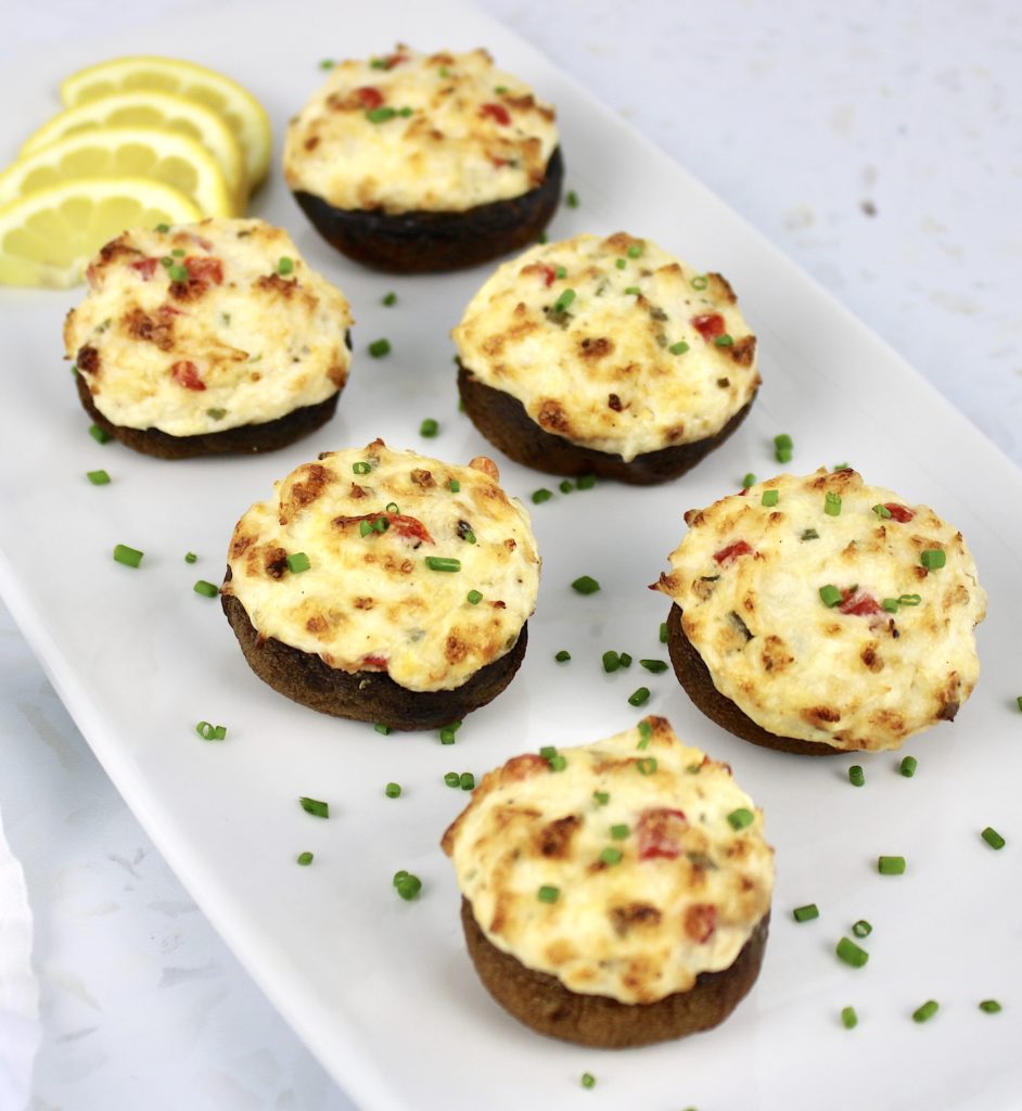 6 Crab Stuffed Mushrooms on white plate with lemon slices and chopped chives