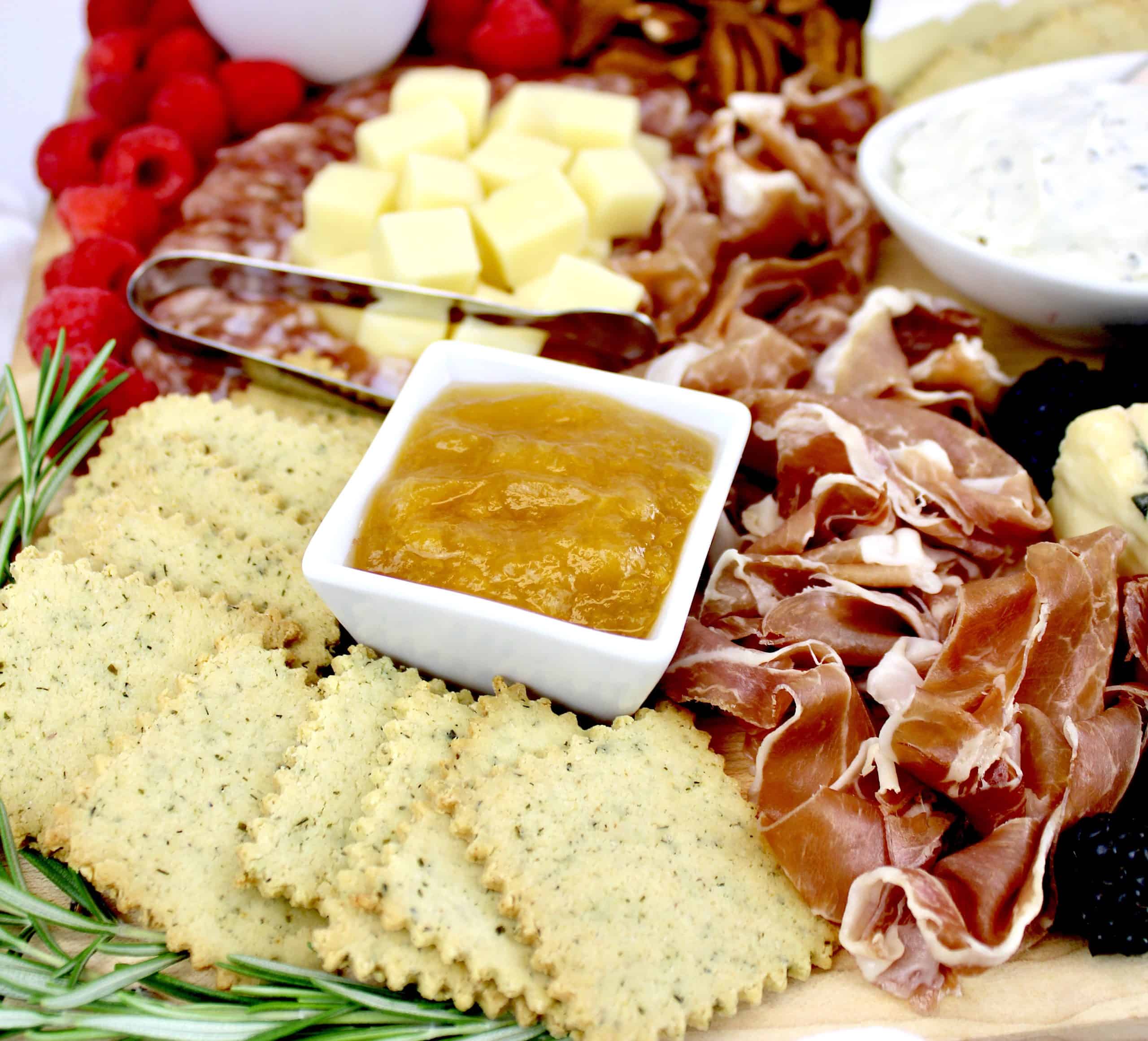 closeup of charcuterie board with crackers prosciutto and apricot jam