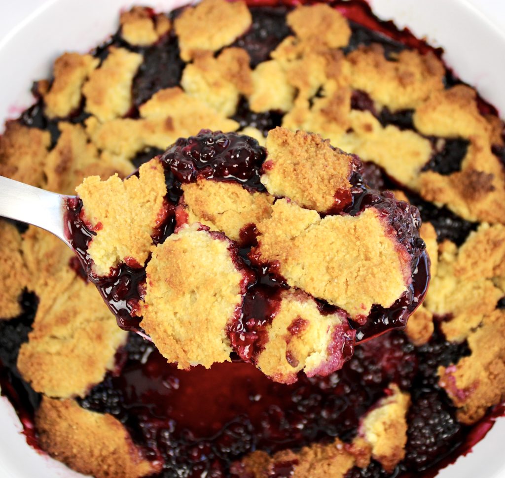 blackberry cobbler with spoon holding up some