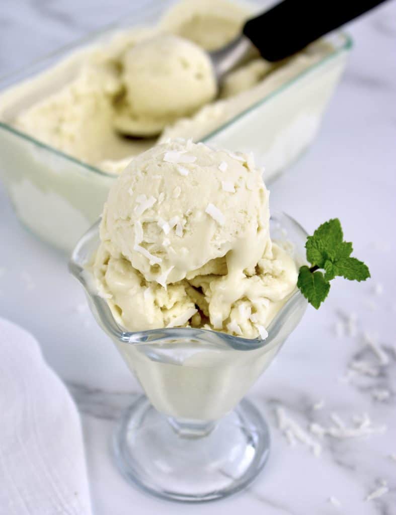 coconut ice cream in glass dish with mint sprig