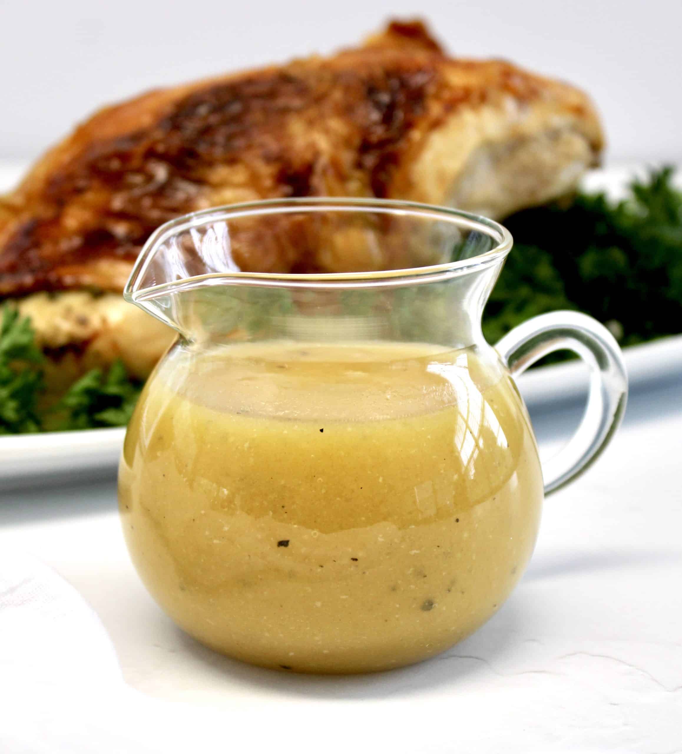 glass serving cup with gravy and turkey in background