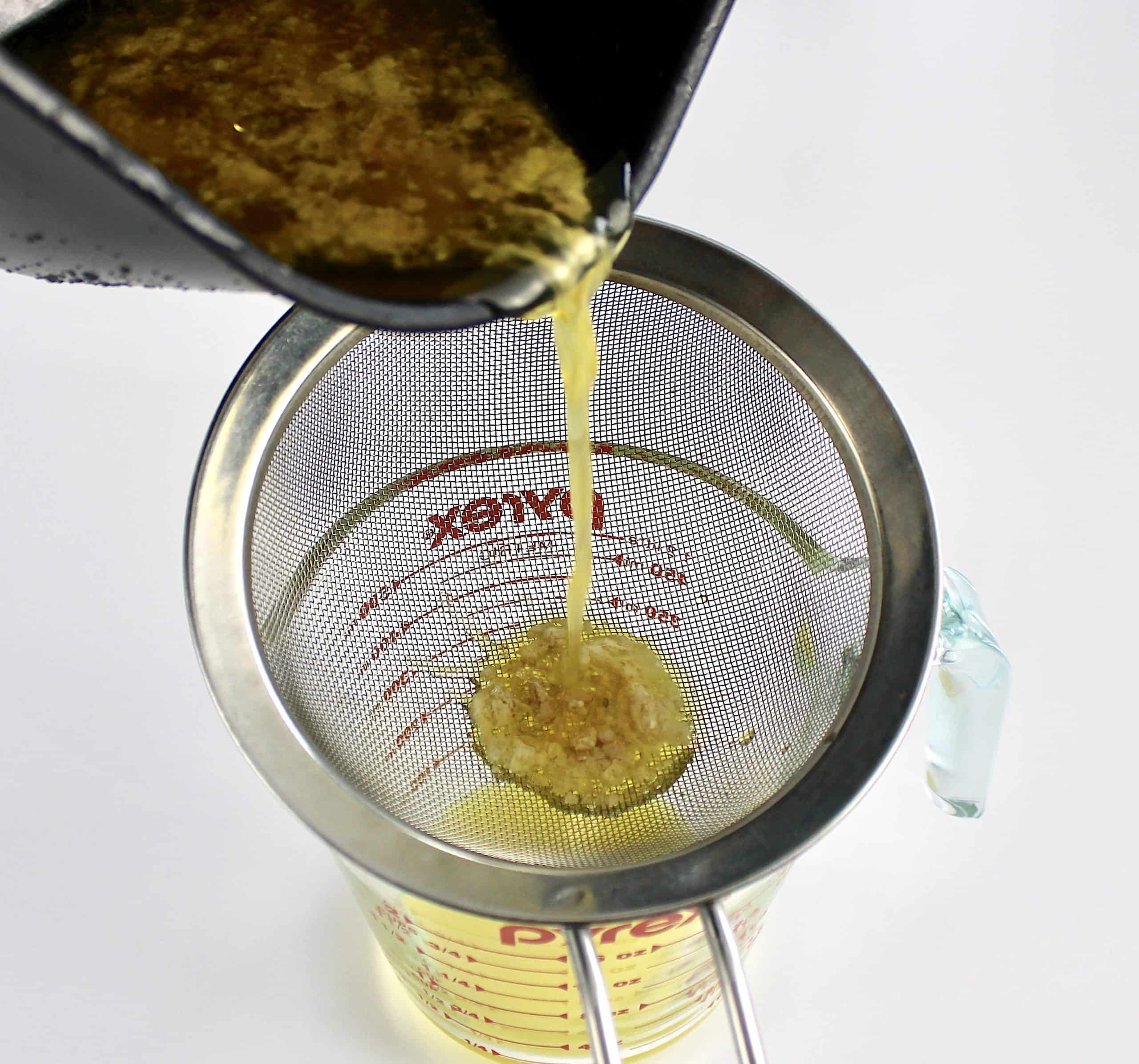 turkey drippings being strained into glass measure cup
