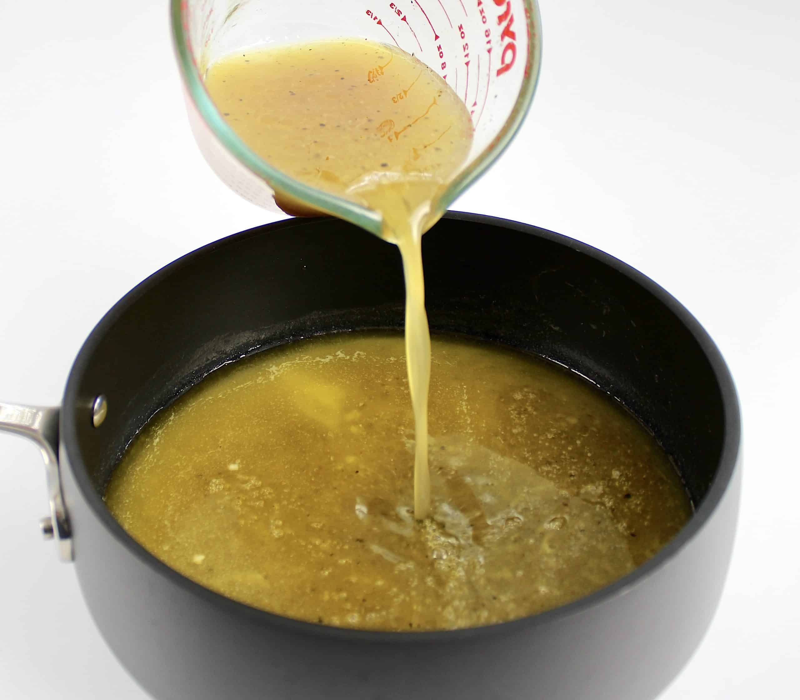 chicken stock being poured into saucepan