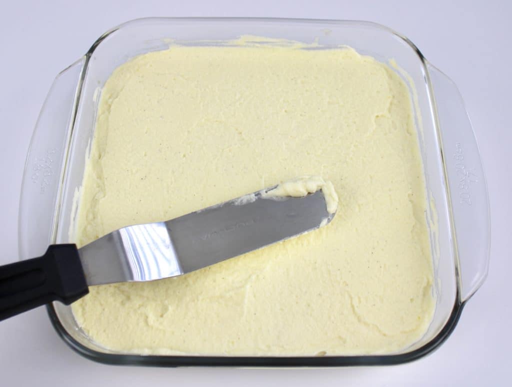 mascarpone cream being spread with spatula in glass dish