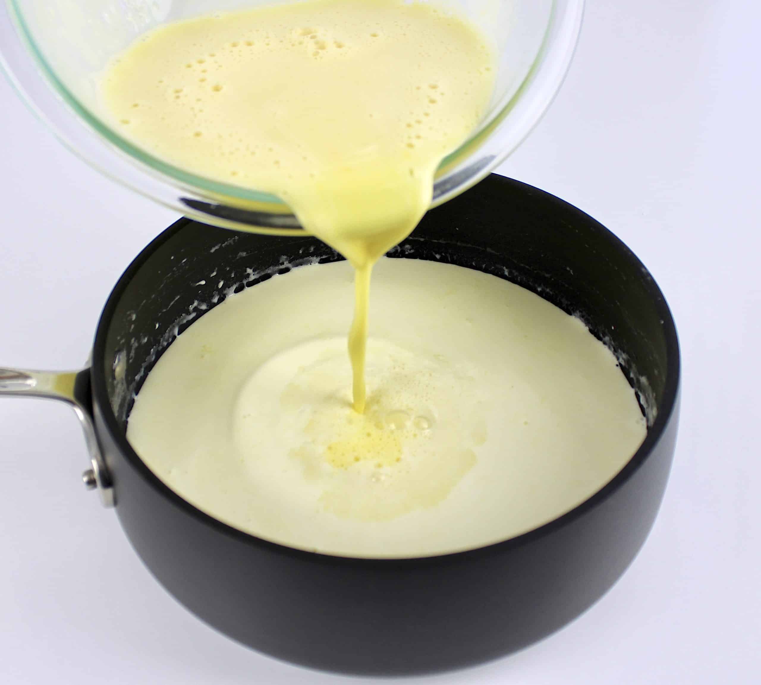 egg mixture being poured into cream in saucepan