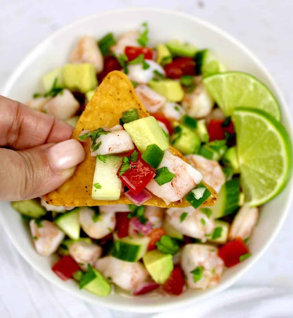 Shrimp Ceviche on tortilla chip being held up over bowl