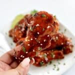 holding up Sticky Asian Chicken Wing with chopped cilantro and sesame seeds