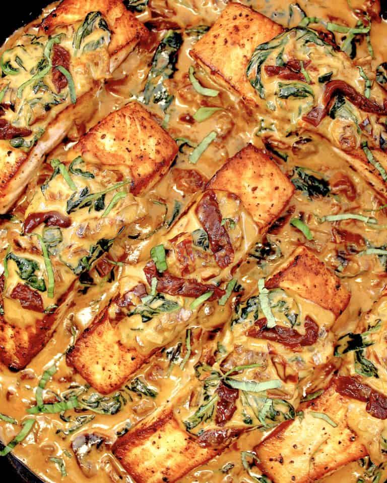 overhead view of tuscan salmon in skillet with creamy sauce