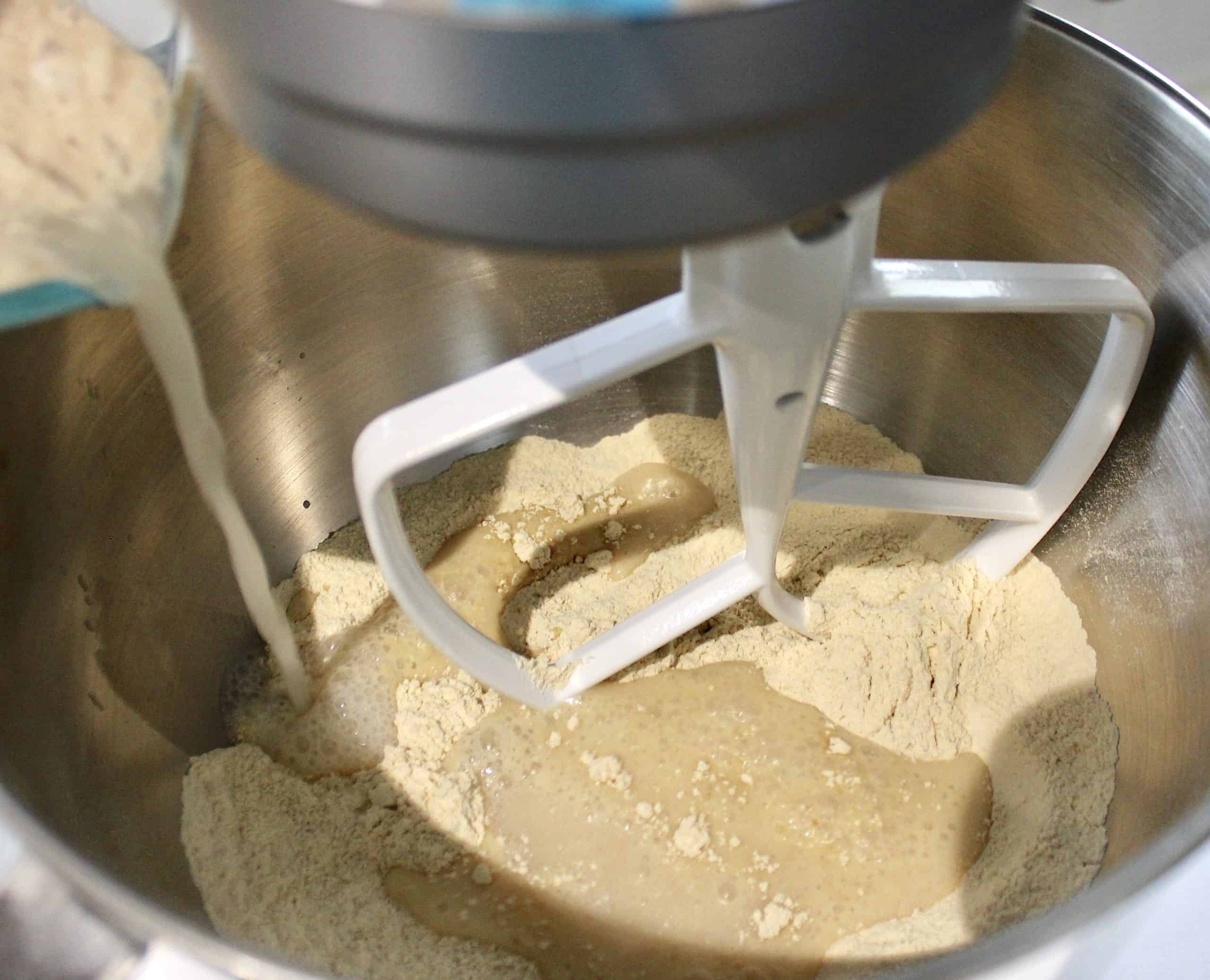 yeast water pouring into stand mixer with dry ingredients