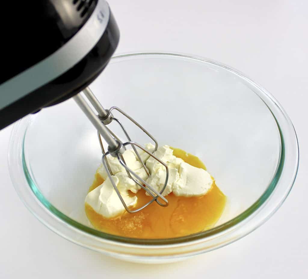 egg yolks and cream cheese in glass bowl unmixed with hand mixer