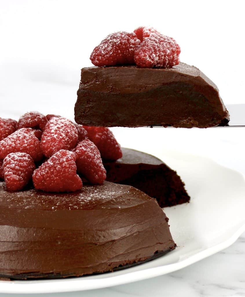 chocolate cake with raspberries on top with slice held up