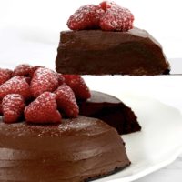 chocolate cake with raspberries on top with slice held up
