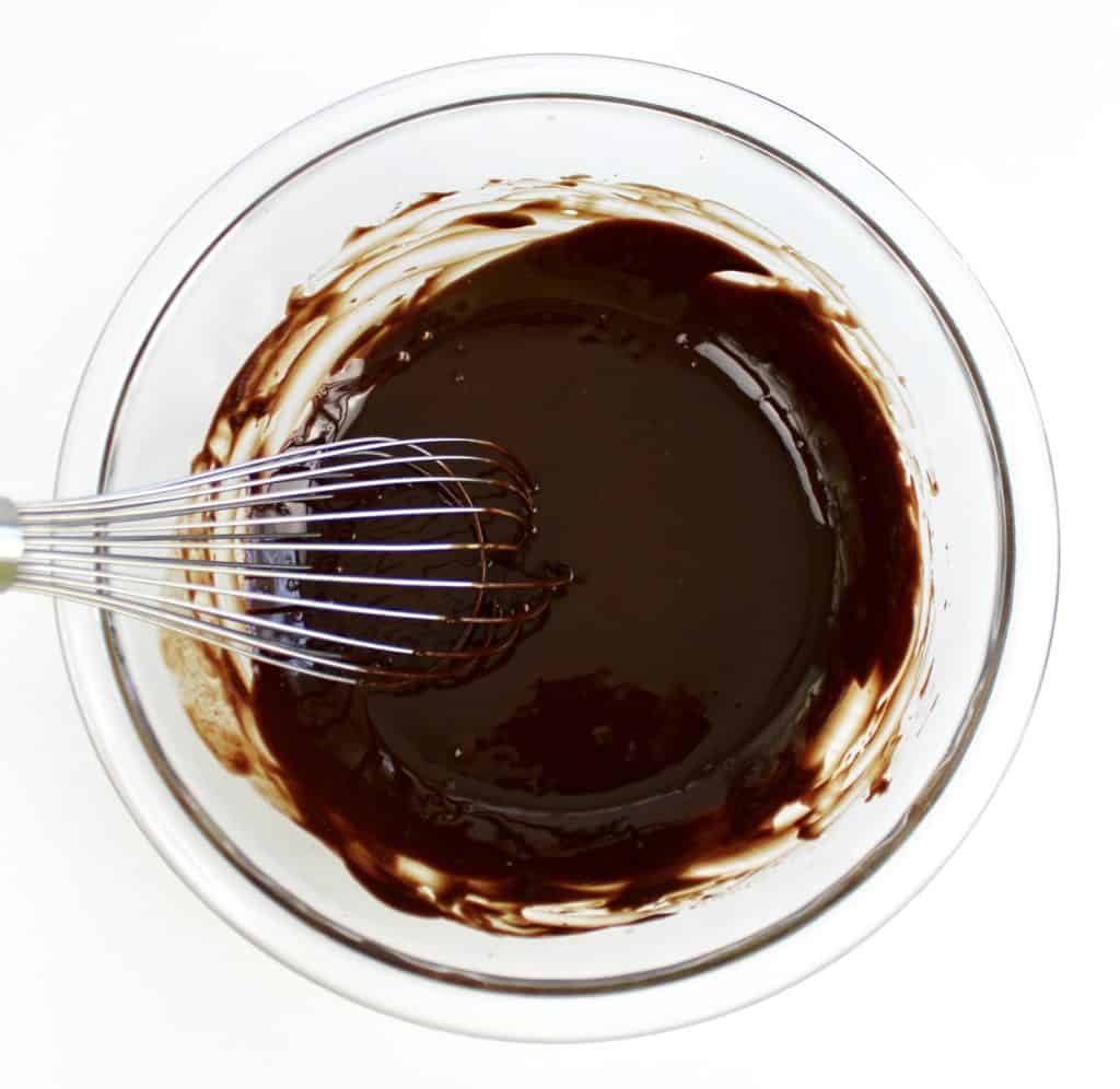 chocolate cake batter in glass bowl with whisk