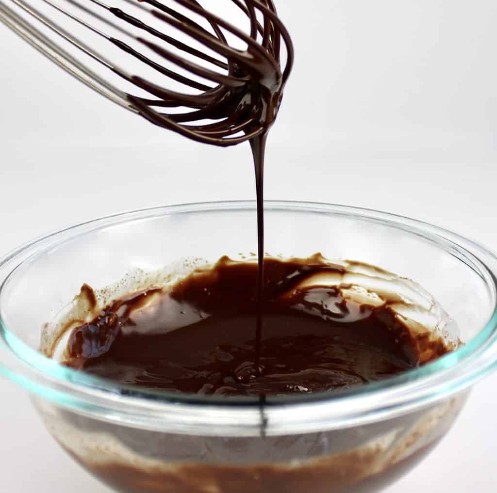 chocolate ganache in glass bowl with whisk dripping