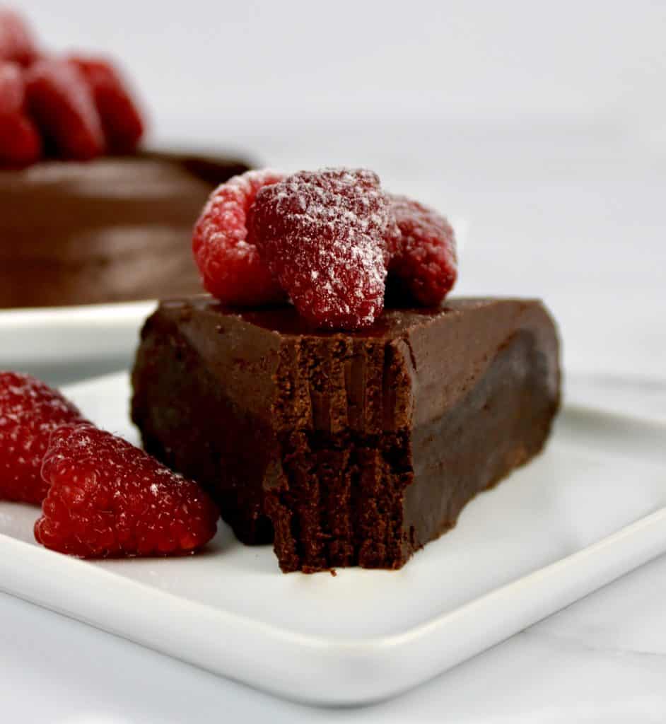 slice of chocolate cake with raspberries on top with bite taken out