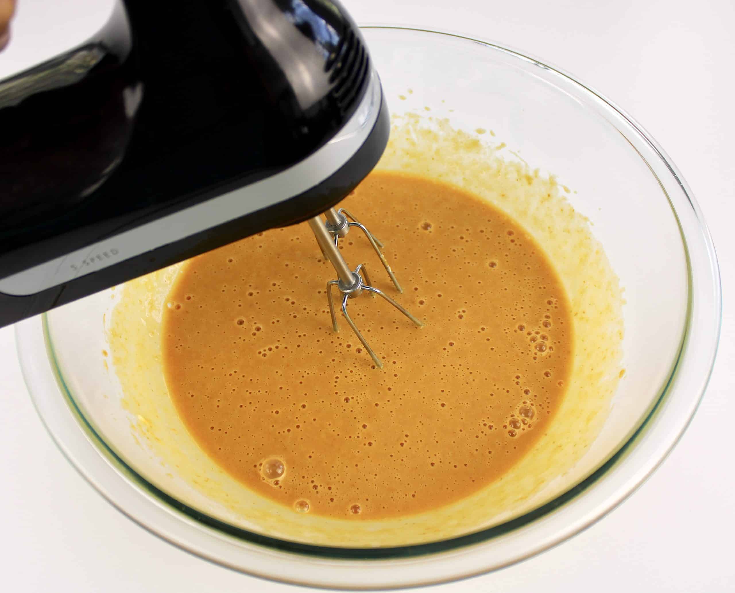 wet ingredients for pumpkin bars being mixed with hand mixer