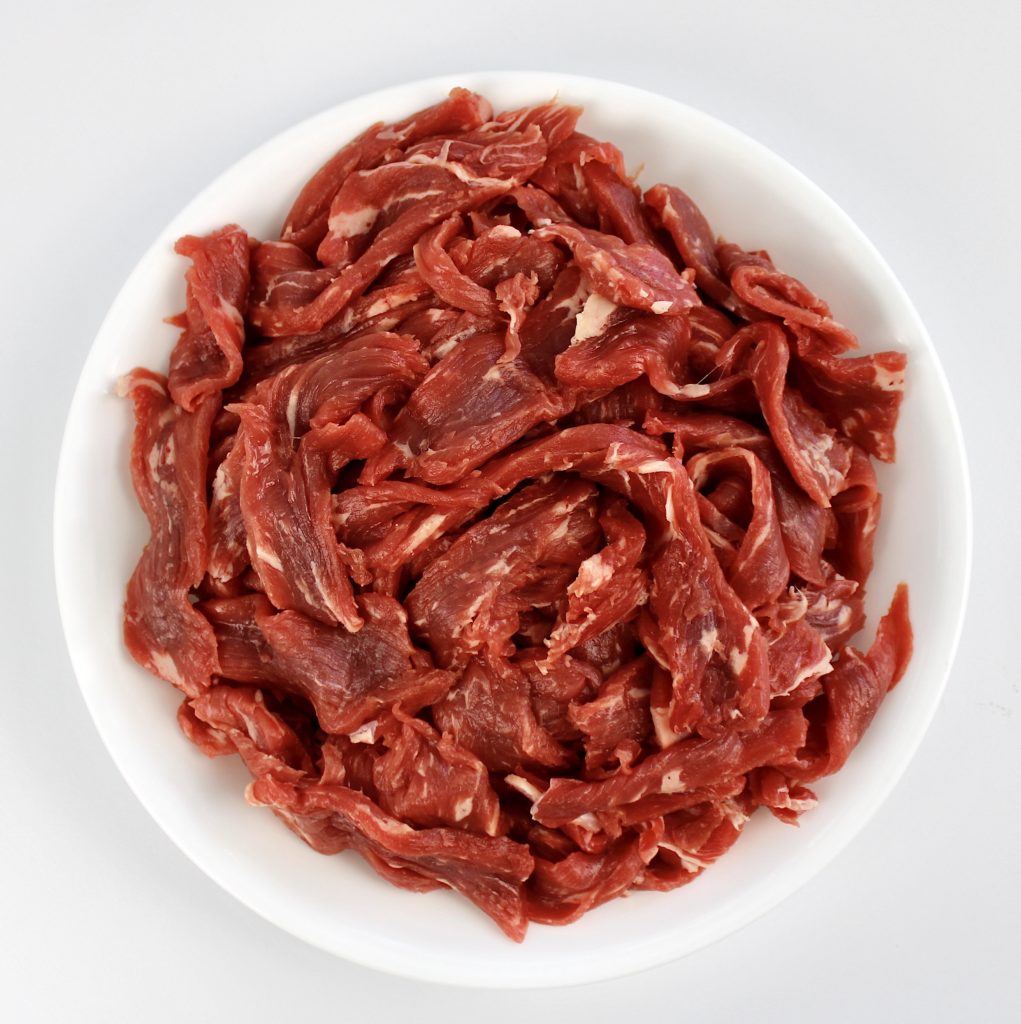 thinly sliced steak in white bowl raw